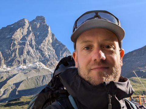 Harry, smiling in a cap and sunglasses, with the Matterhorn behind him